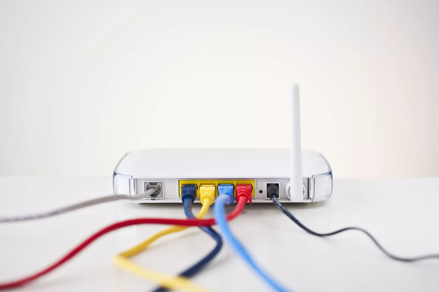 White wireless router with four ethernet cables plugged in